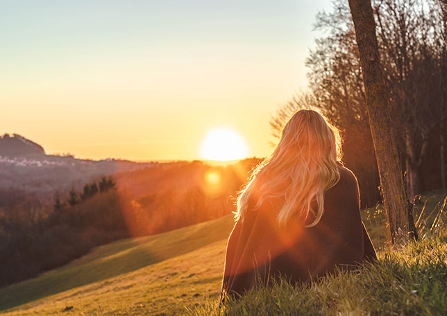 Mujer sentada en el pasto en el atardecer