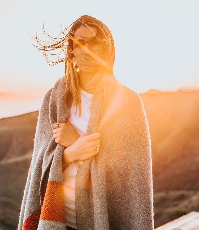 Mujer cubierta con una manta sobre sus hombros al atardecer - Vitamina D 