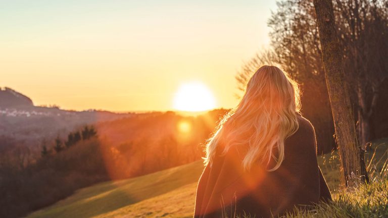 Mujer de espaldas al sol del atardecer