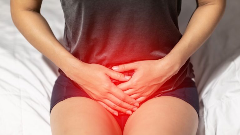 Mujer con las manos en su pelvis - Infección de las vías urinarias