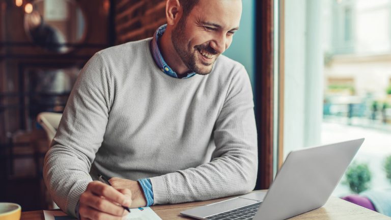 Hombre sentado en una cafetería trabajando en una computadora -PSA